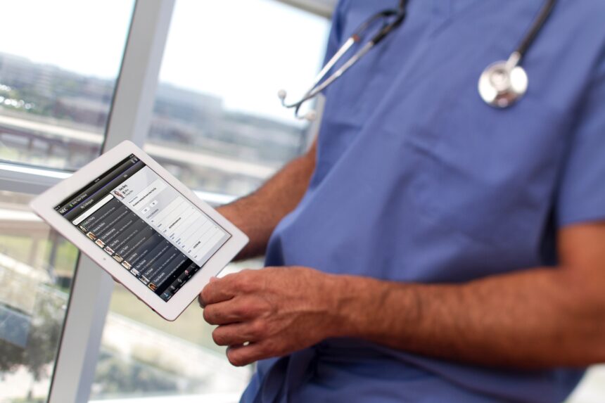 A doctor in scrubs holding a computer