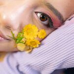 close up shot of woman with yellow flowers on her cheek