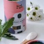 container of collagen powder near white flowers and green leaves