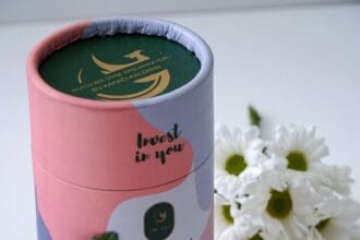 container of collagen powder near white flowers and green leaves