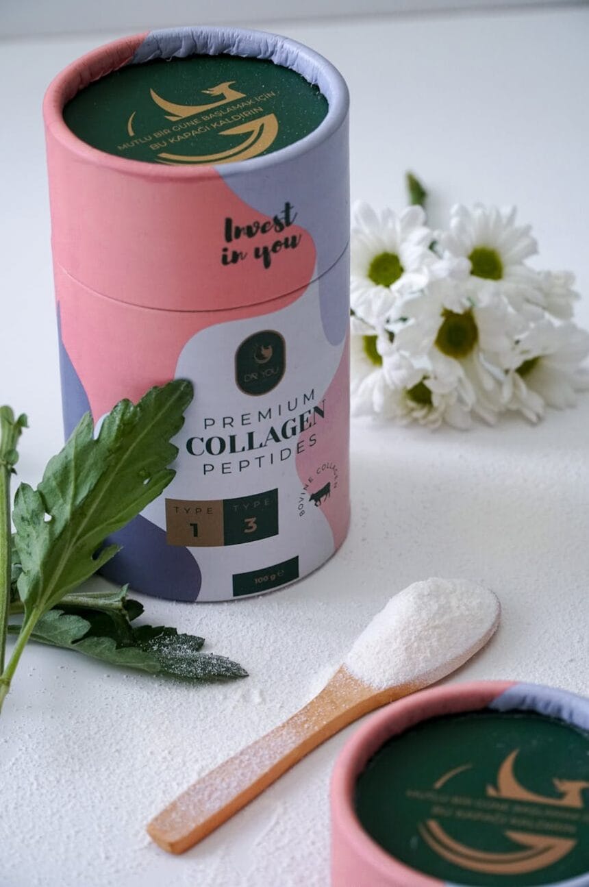 container of collagen powder near white flowers and green leaves