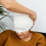 a person putting a bandage on a woman s head