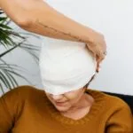 a person putting a bandage on a woman s head