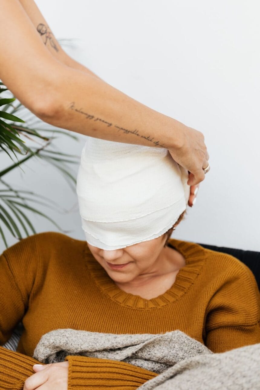 a person putting a bandage on a woman s head