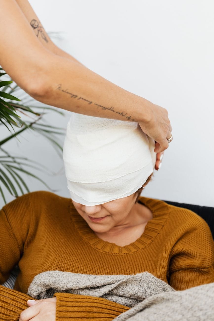 a person putting a bandage on a woman s head