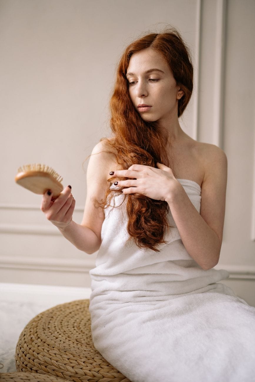 photo of a woman with red hair holding a brown brush